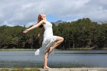 Fototapeta na wymiar Happy woman in white dress posing showing legs in nature