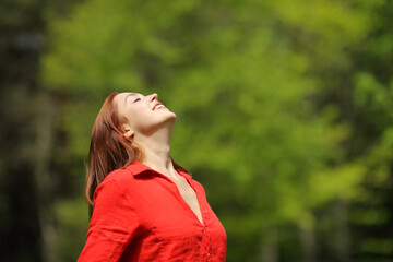 Happy woman in red breathing fresh air in a forest