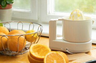 making orange juice. Squeezing the juice of a natural fresh oranges. Electric juicer and fresh...