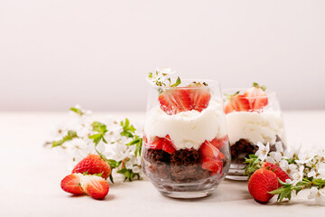 Sweet dessert in glass with biscuit, strawberry and whipped cream
