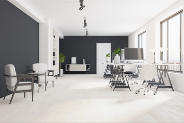 Sunny monochrome style coworking office with stylish white and black armchairs, tables and bookcase, modern computer monitors and big windows