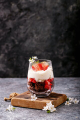 Sweet dessert in glass with biscuit, strawberry and whipped cream