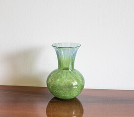 Mid-century modern green art glass vase on a wooden sideboard
