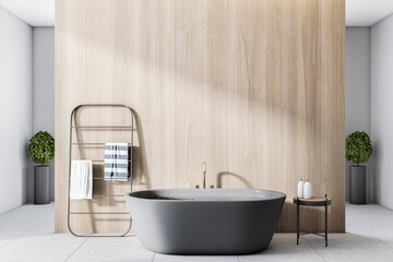 Obraz na płótnie Canvas Modern bathroom with wooden partition behind black bath, towel rail and stylish coffee table for shampoo