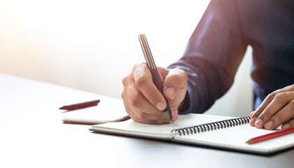 Businessman hand holding writing pen memo into notebook paper on table desk office. Workplace for business and student, writer with copy space. business working and learning education concept.