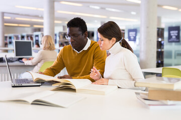 Adult female and male students working in library. High quality photo