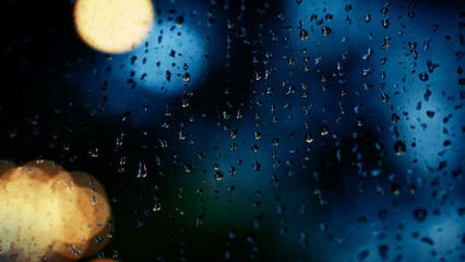 Rain drop on window at night. Condominium or apartment living room window on rainy season night in Bangkok Thailand. Outside window is blurred bokeh of raining city light and natural tree and sky. 