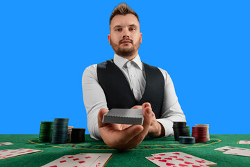 Male croupier at the casino at the table isolated on blue background. Casino concept, gambling, poker, chips on the green casino table.