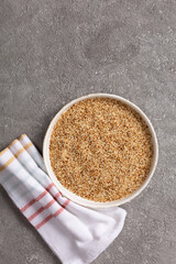Sesame seeds in a bowl on a gray concrete background.