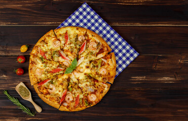 Close up on homemade seafood pizza with shrimp, crab sticks, bell peppers topping on wooden tray...