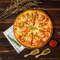 Banner of homemade seafood pizza with shrimp, crab sticks, bell peppers topping on wooden tray, table, decorated by tomato sauce, ketchup, oregano ingredients with napkin in kitchen and copy space.