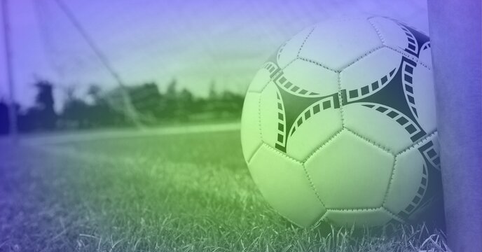Composition of football on grass pitch by goal post with copy space and purple tint