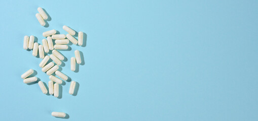 medical powder in white capsules on a blue background. Treatment pills, nutritional supplements, copy space