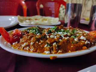 Stock Photo of delicious mouthwatering paneer butter masala or cheese cottage curry, decorated with fresh coriander, tomato and cheese. popular dish in India.