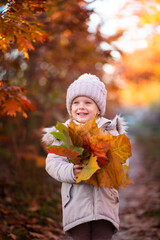 baby girl in autumn park playing with leaves