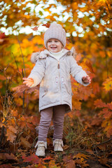 baby girl in autumn park playing with leaves