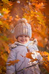 baby girl in autumn park playing with leaves