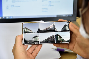 Monitoring buildings and shops' security by using CCTV application on mobile phone when owner stayed outside concept. Selective focus on mobile phone.