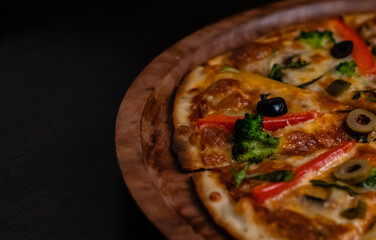 Crop and high angle view of picante pizza on black surface.
