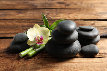 Fototapeta na wymiar Spa stones, bamboo stems and beautiful orchid flower on wooden table