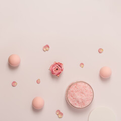 Rose scented sea salt in jar with cap and rose flowers. Cosmetic product top view, trend pink pastel colored