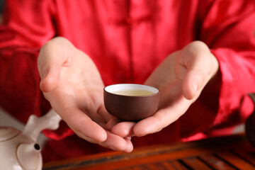Fototapeta na wymiar Master offering cup of freshly brewed tea during traditional ceremony at table, closeup
