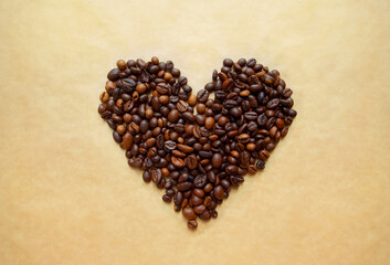 Heart of coffee beans on a brown craft paper background. Coffee love concept