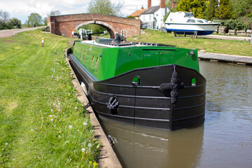 Wide beam canal boat in green with brass fittings on the river soar - stock photo