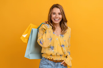 beautiful attractive smiling woman in yellow shirt and jeans holding shopping bags - obrazy, fototapety, plakaty