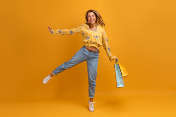 beautiful attractive smiling woman in yellow shirt and jeans with shopping bags