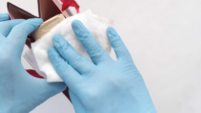 hand in latex gloves wapping a gift box with tissue 