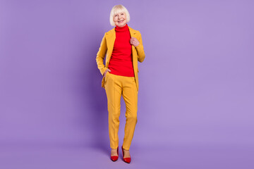 Full body photo of cheerful nice short hairdo aged lady wear yellow suit isolated on purple color background