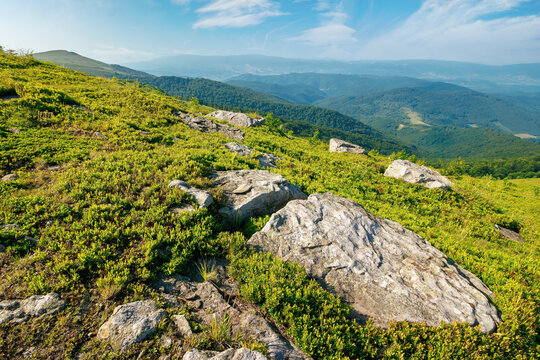 summer mountain landscape with stones on the hill. wonderful view in to the distant valley on a sunny morning. fluffy clouds above horizon