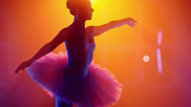 Graceful ballerina in tutu dancing elements of classical ballet in colorful neon light. Multi-colored floodlight backlight. Smoke on stage. Art concept.