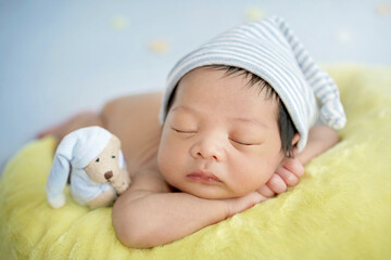 Close up newborn baby wearing a blue and white striped hat. Newborn sleeping on a crescent moon...