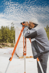 Geodetic works. Building a house, a builder looks at the level on a tripod