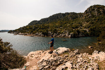 Fototapeta na wymiar rear view of male tourist standing on stone and enjoying the sea and mountain scenery