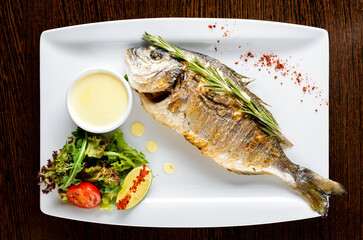 fish dorada with fresh salad in restaurant