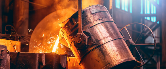 Metal cast process, long banner image. Molten liquid iron pouring from ladle container into mold.