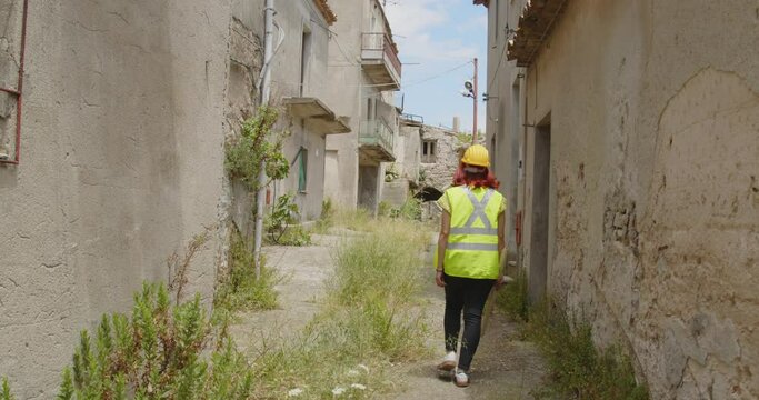 Giovane ragazza ingegnere con caschetto giallo visita la citt&agrave; distrutta dalla guerra