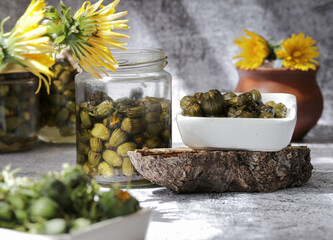 False capers made from young dandelion buds in glass jar.