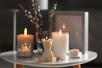 Fototapeta na wymiar Beautiful body shaped candles and willow bouquet on table indoors