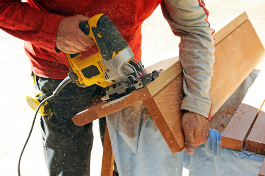 Carpintero cortando con una sierra de calar los escalones de madera de haya para la escalera del interior de una casa