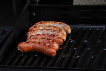 Close up on a grilled sausages on a black grill