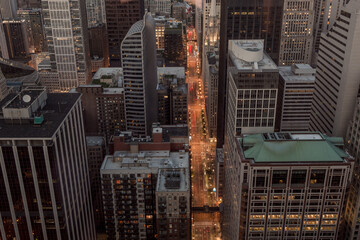 Long street cutting through downtown Chicago at dusk with lights