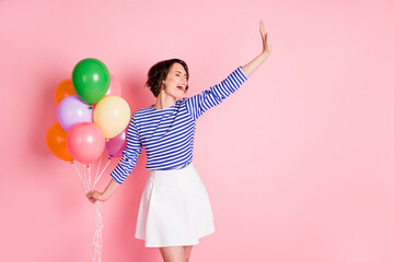 Obraz na płótnie Canvas Photo of young attractive excited crazy smiling positive girl hold balloons hold hand say hi isolated on pink color background