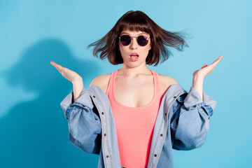 Photo of excited cute young woman wear denim shirt dark eyewear rising arms isolated blue color...
