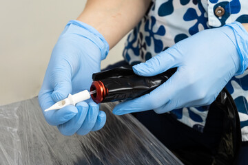 The process of preparing tools for permanent makeup. Master's hands in blue gloves.