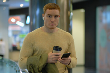 young man using smartphone and listens to music in bluetooth headphones. lonely man in autumn...