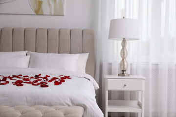Beautiful red rose petals on bed in room